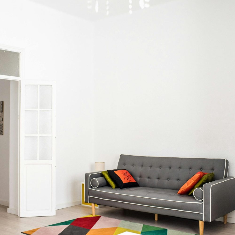 Modern living room with a stylish gray sofa and colorful geometric decor, featuring a chandelier.